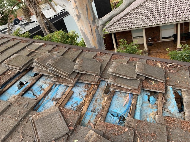 A photo showing damaged waterproof sarking beneath broken roof tiles