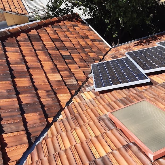 A photo of a newly restored tile roof with clean tiles and clean blue solar panels