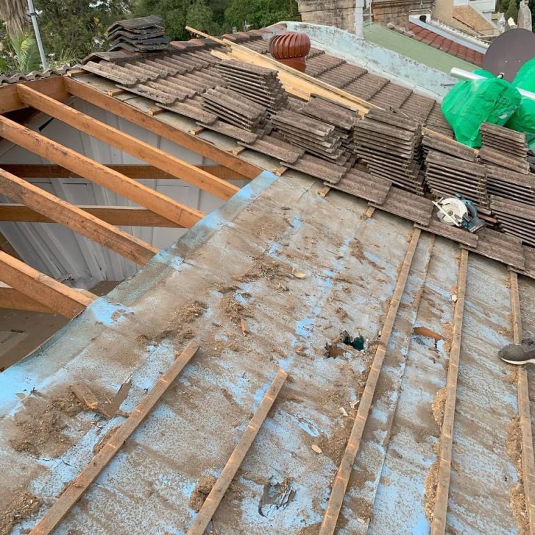 A roof which is covered with blue plastic while the roof battens beneath are being replaced