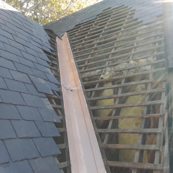Damaged slate roof valley with roofing materials removed to expose the structure beneath