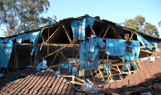 Severely damaged tiled roof with the roof structure exposed